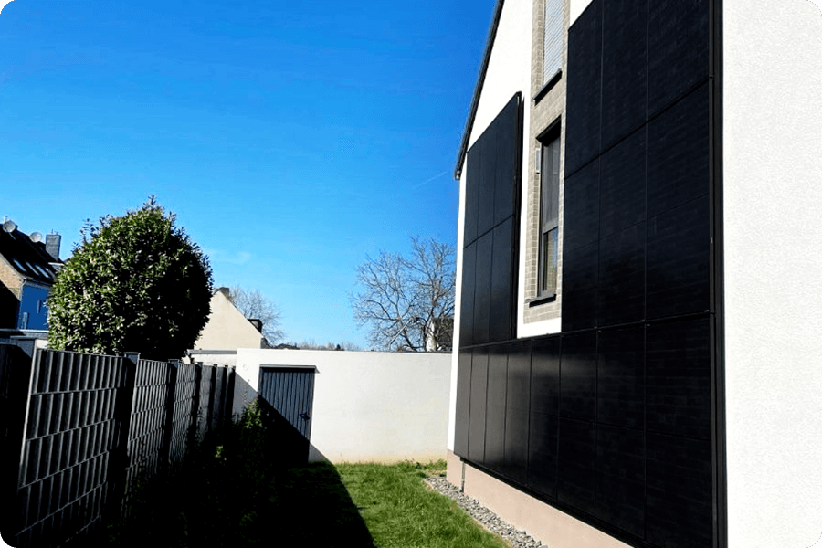 Full-black PV modules vertically installed on a residential façade, demonstrating architectural integration and low-light suitability.