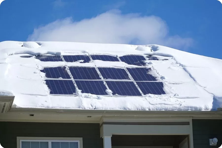 Rooftop photovoltaic panels covered with a thick layer of snow, reducing system efficiency.